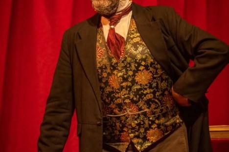 a man wearing a suit and tie standing in front of a curtain