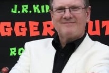 Man in white jacket stands arms crossed, colorful text in background.